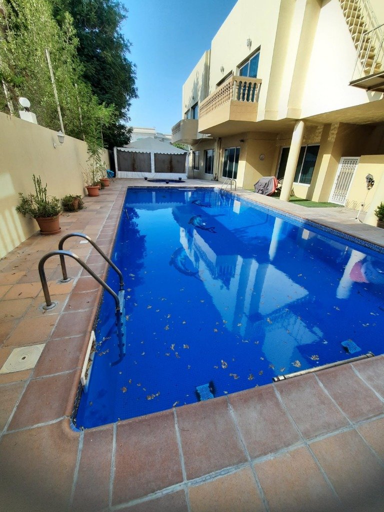 Residential swimming pool with clear blue water and villa surroundings